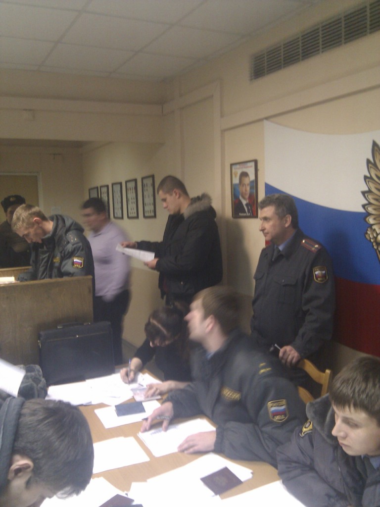 Составление протоколов на задержанных. Снявший шарф сотрудник центра "Э" помогает полицейским. Актовый зал ОВД Раменки.